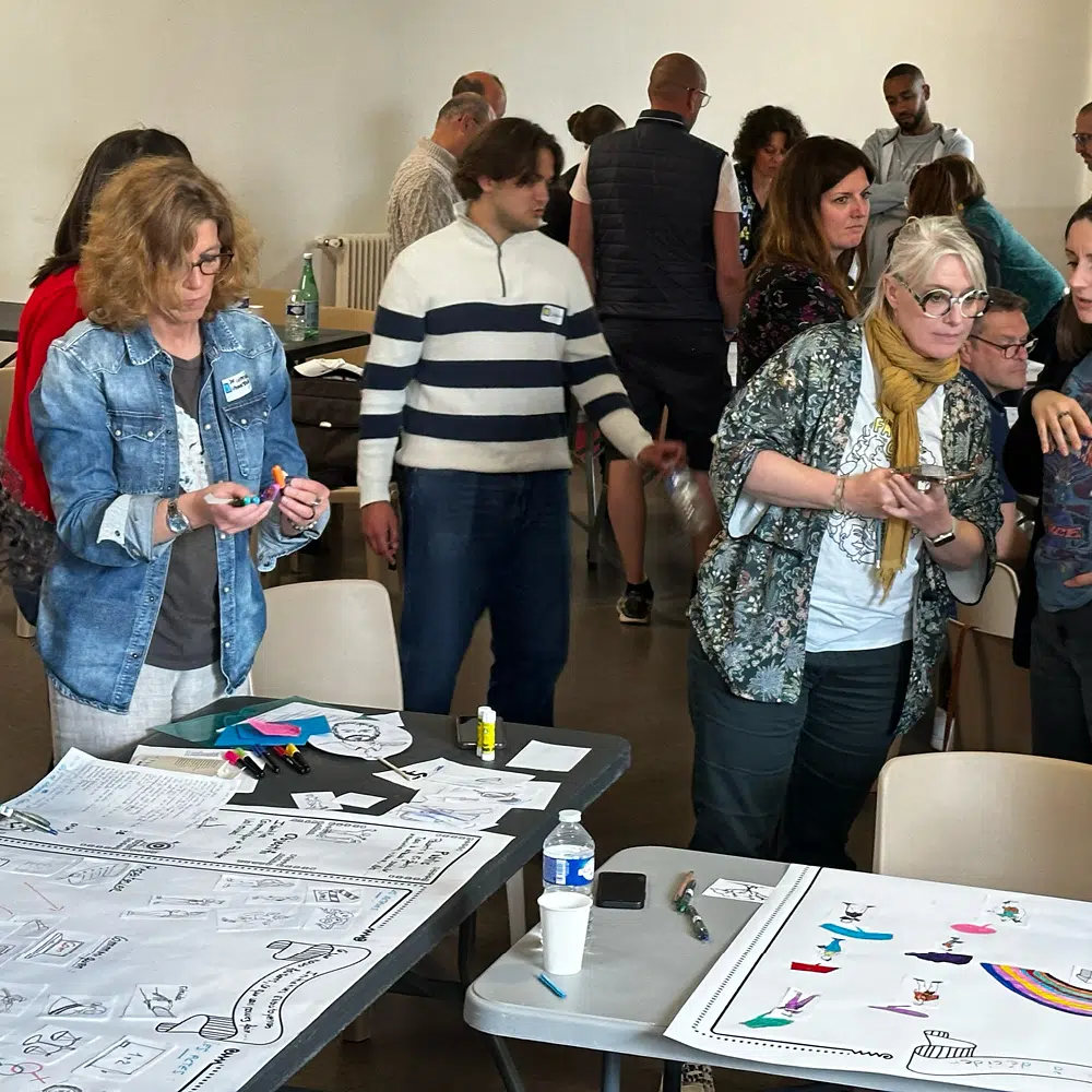 Atelier de co-création et de workshop créatif animé par Joris Hauselmann avec des illustrations et planches de bande dessinée étalées sur des tables.